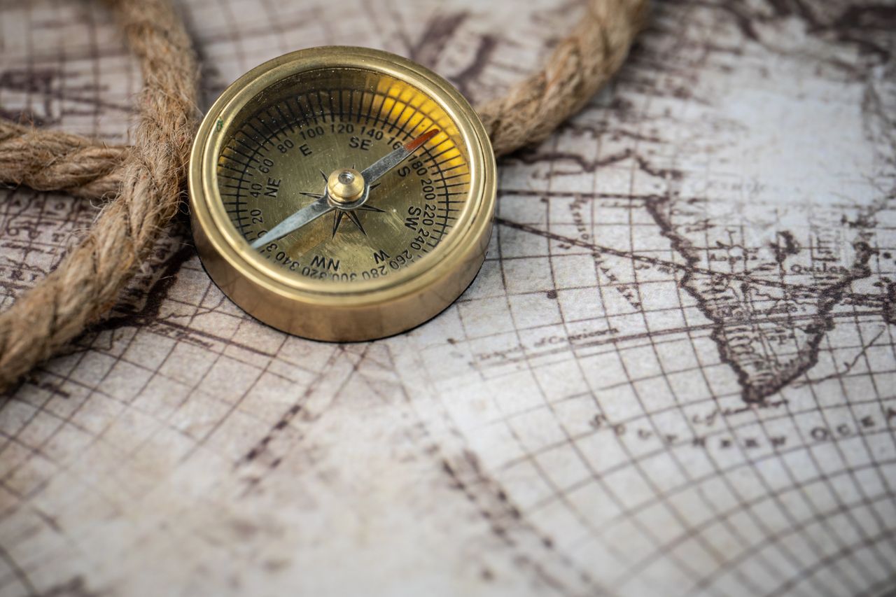 why-choose-us A vintage brass compass rests on an antique map with a nautical rope, evoking exploration and discovery.