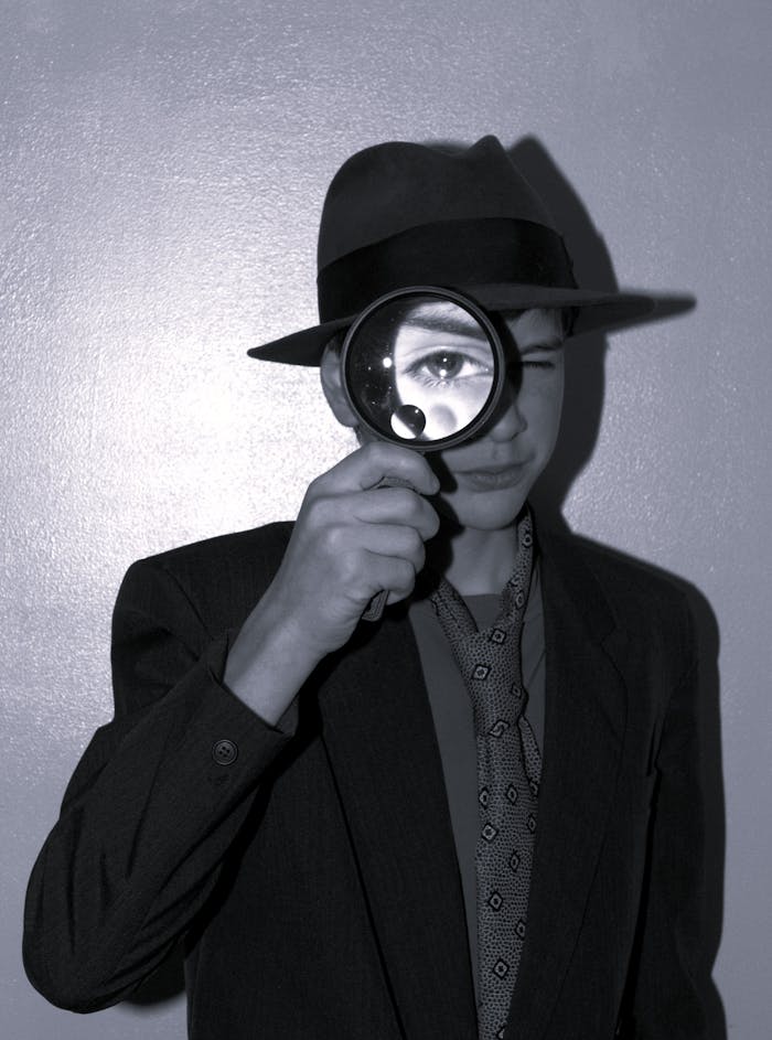 gallery-3 A teenager in vintage attire holds a magnifying glass, evoking a classic detective mood.