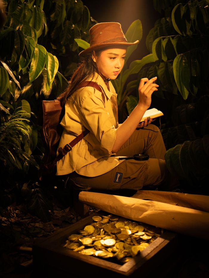 services-02 Adventure scene of a young explorer finding a trove of gold coins in the jungle.